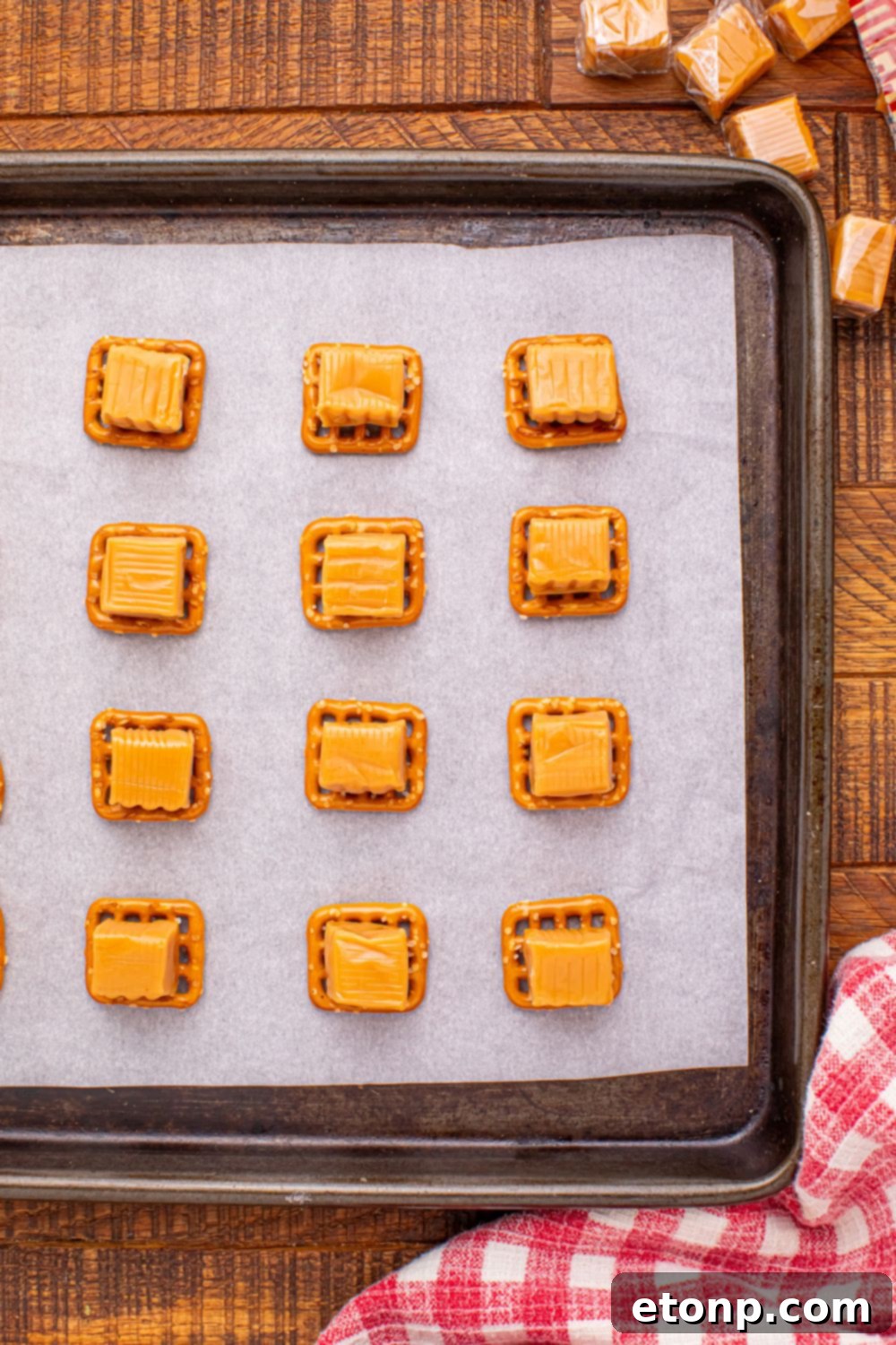 Sweet and Salty Caramel Apple Pretzel Bites 7 caramels sitting on top of pretzel squares on a baking tray