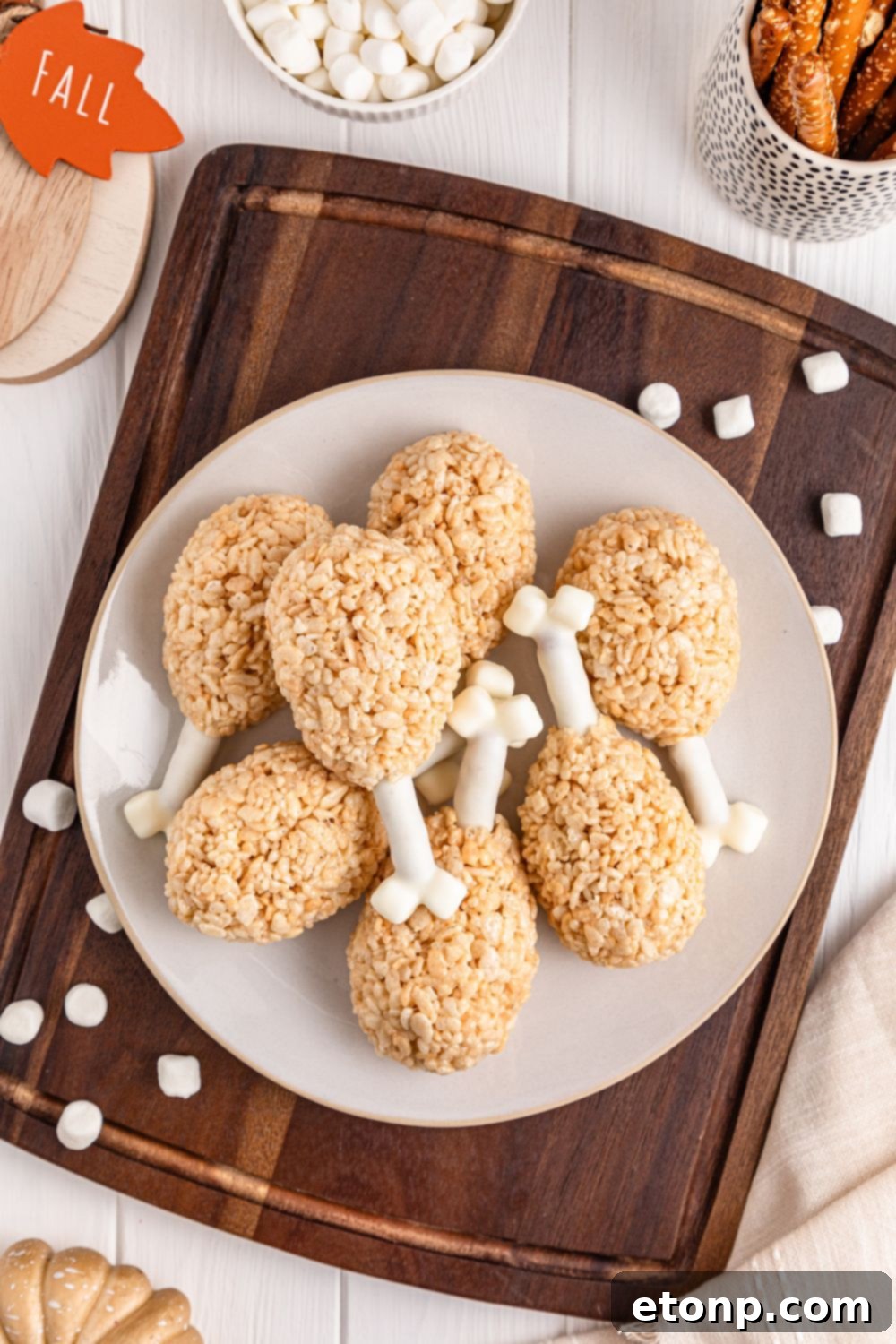 Rice Krispie Treat Turkey Legs sitting on a platter on the table on a plate with holiday decor scattered on table 