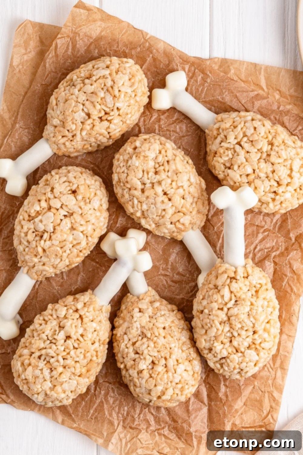 Rice Krispie Treat Turkey Legs spread on parchment paper sitting on a white table