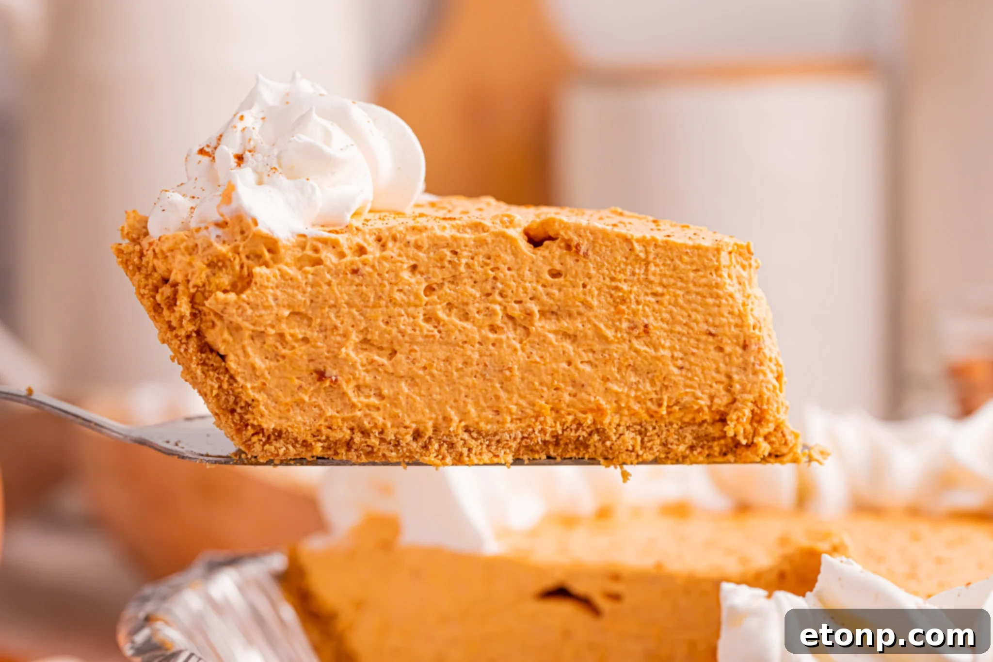 A perfectly sliced Marshmallow Pumpkin Pie, with a slice being gently lifted, revealing its creamy, airy filling and crisp graham cracker crust, ready to be enjoyed.