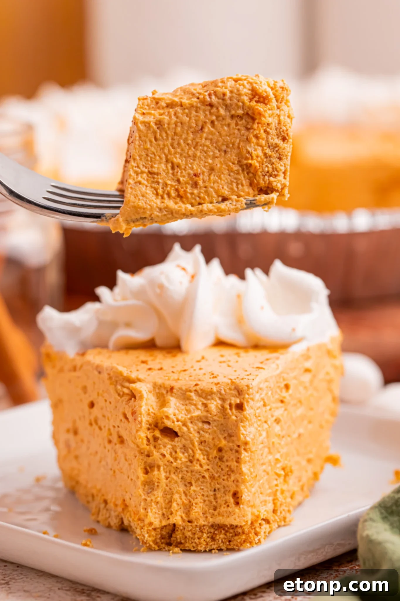 A delectable slice of Marshmallow Pumpkin Pie, with a fork gently lifting a perfect, airy bite, poised gracefully above the plate, highlighting the irresistibly fluffy texture of the filling and the crisp, inviting crust.