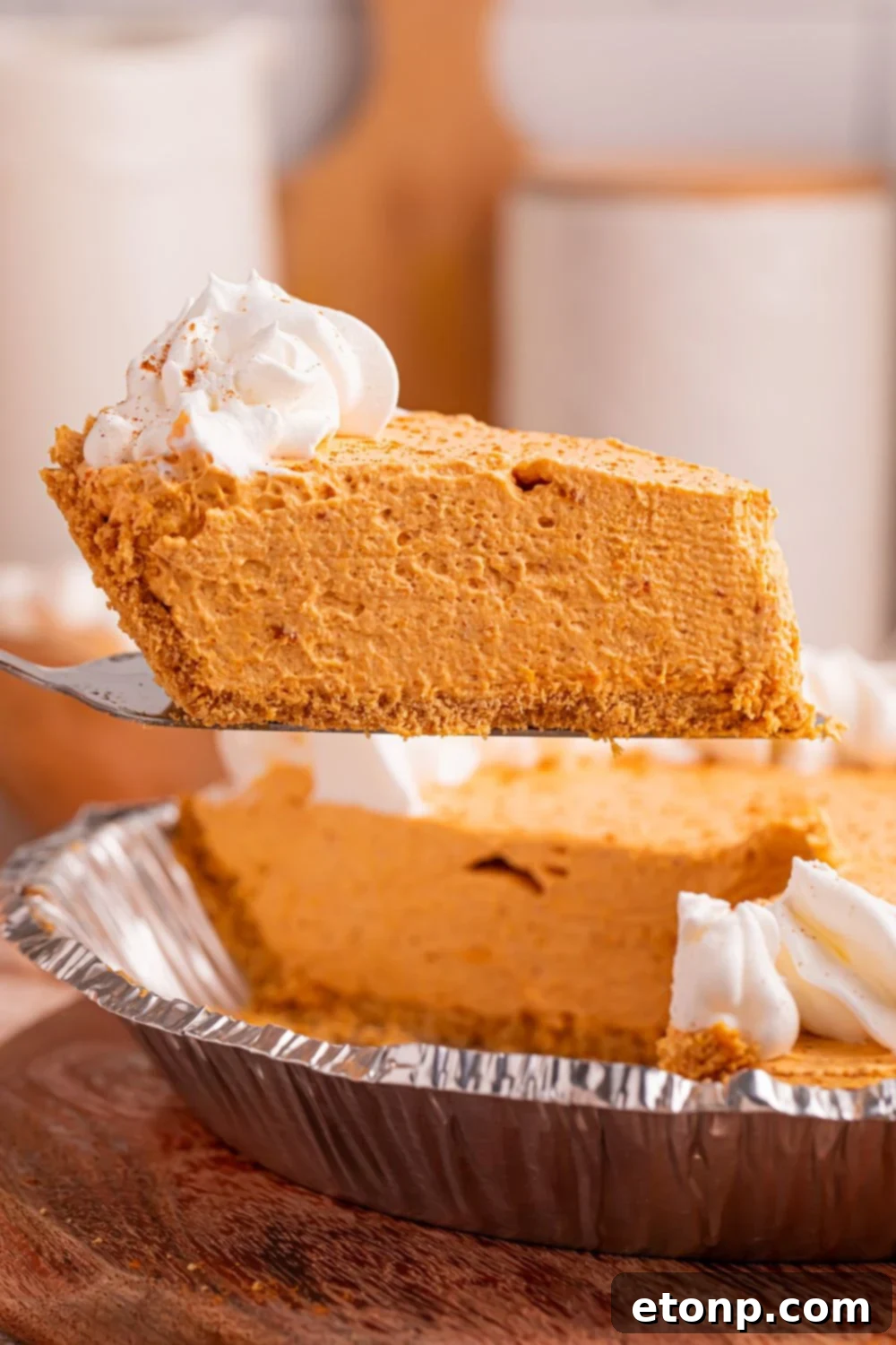 A perfectly portioned slice of Marshmallow Pumpkin Pie being skillfully lifted out of its pie plate with a spatula, gracefully showcasing the impeccable consistency of the filling and the clean, precise cut of the crust.