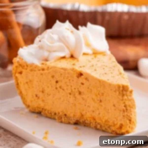 A slice of Marshmallow Pumpkin Pie on a plate, with crumbs scattered around it on the table, showcasing the delicious crust and fluffy filling, ready to be enjoyed.