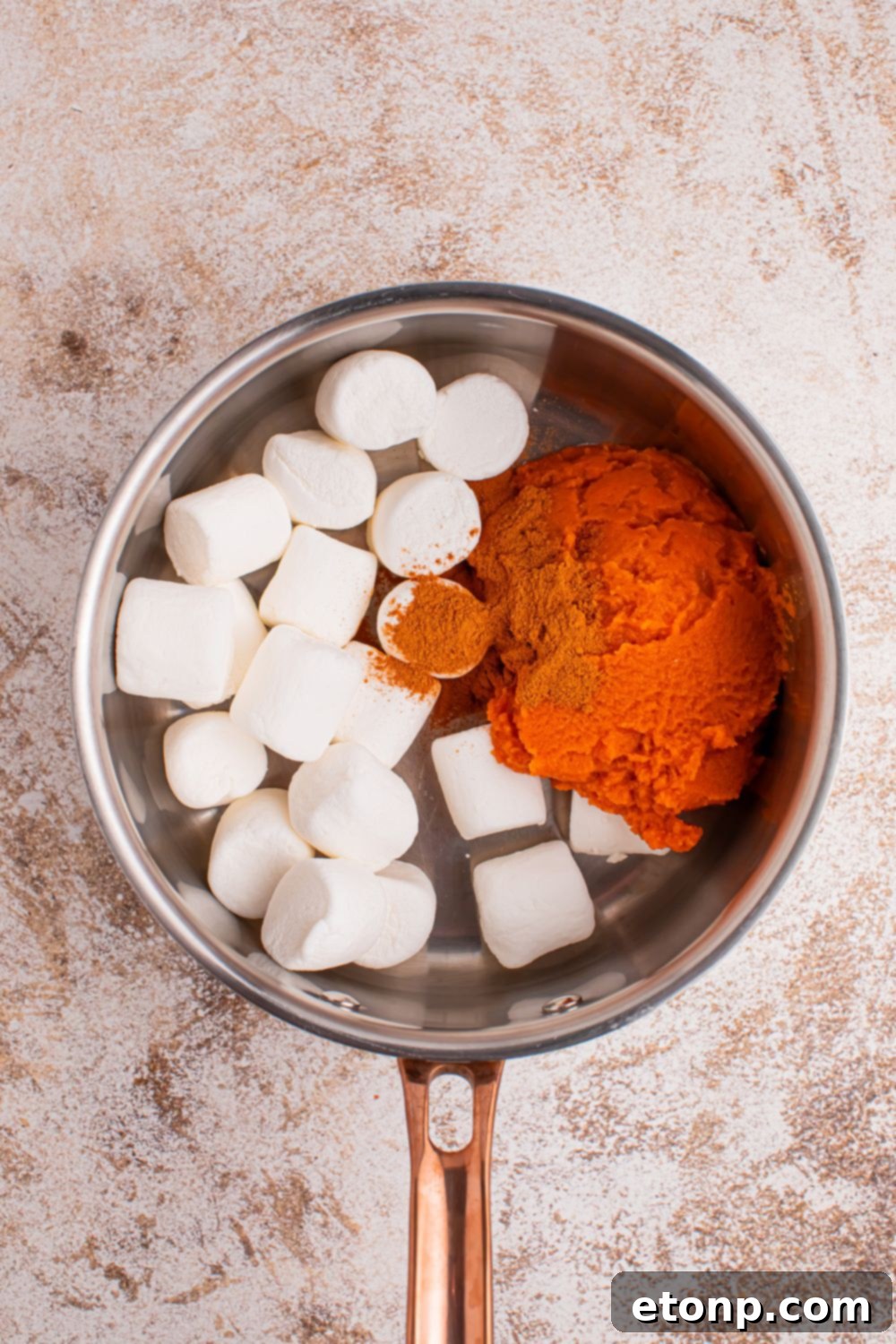 A culinary still life featuring large marshmallows, a container of pumpkin pie spice, and a can of pumpkin puree thoughtfully arranged in a saucepan on a table, symbolizing the initial steps of combining ingredients for the pie filling.