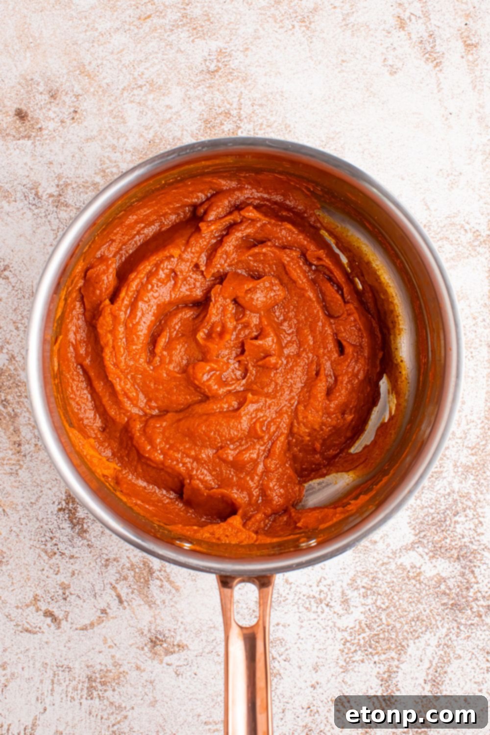 The smooth, vibrant orange pumpkin batter gently simmering in a saucepan, beautifully illustrating the rich color and creamy, luscious texture of the Marshmallow Pumpkin Pie filling as it cooks before the cooling process.