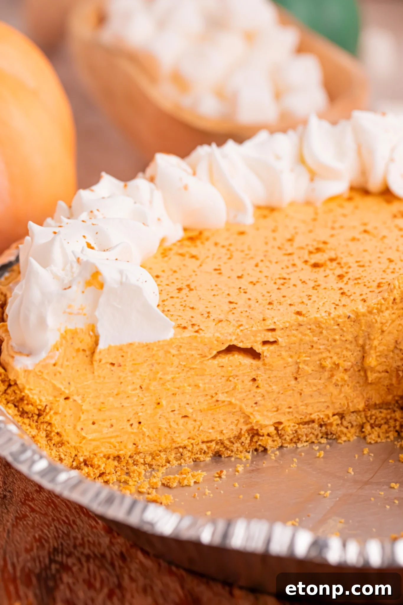 A perfectly assembled Marshmallow Pumpkin Pie resting in its elegant pie dish, with one meticulously cut slice already removed, providing a tantalizing glimpse of the beautifully set, creamy filling and the perfectly intact crust.