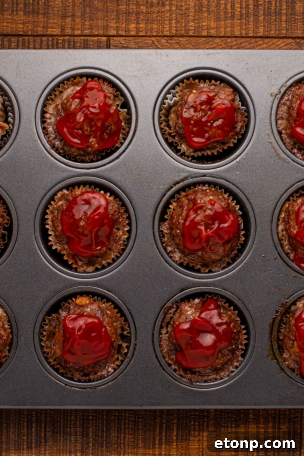 Meatloaf Cupcakes in a muffin tin with ketchup on top of each meatloaf