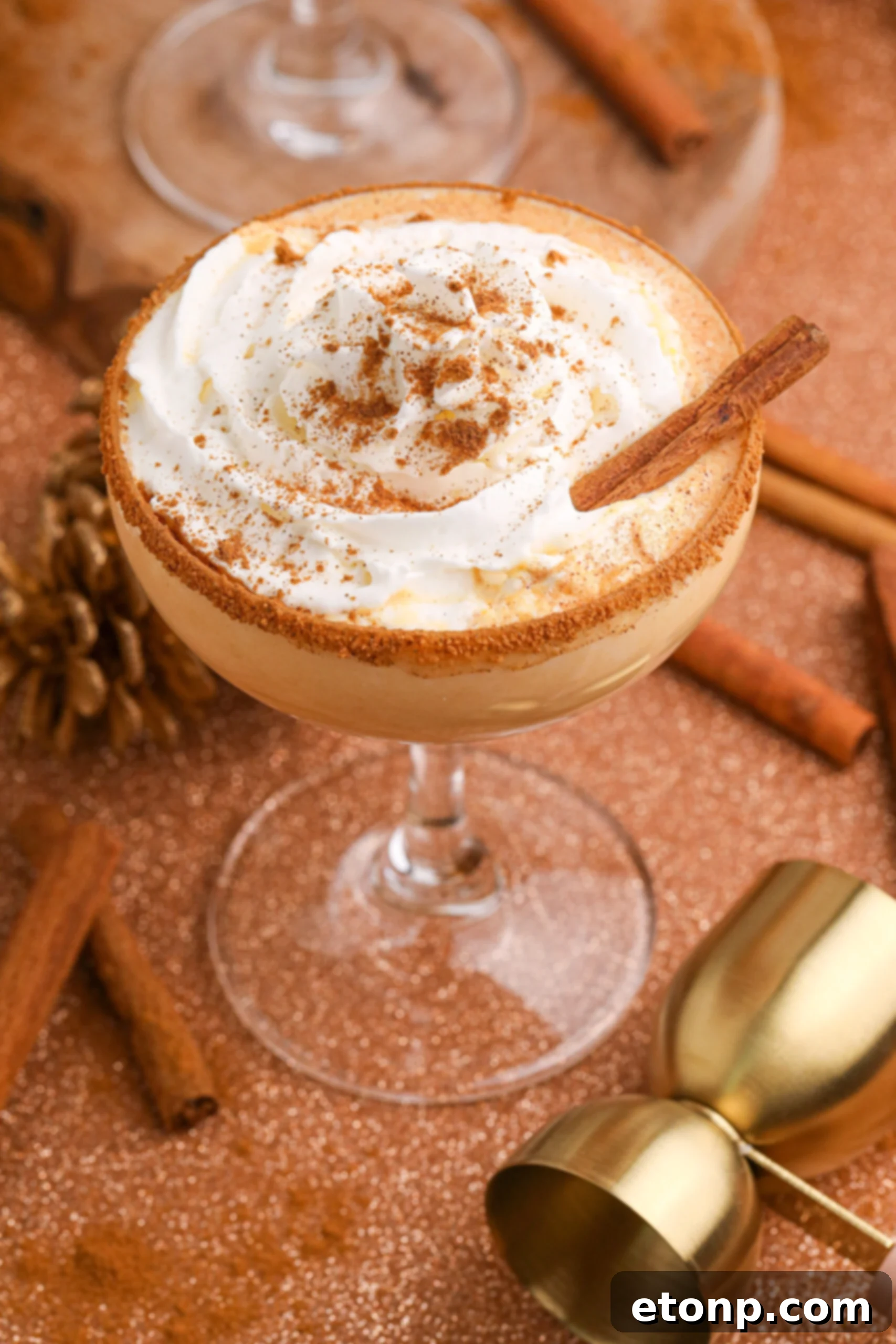 Pumpkin Pie Martini in a glass on a table decorated for a holiday with cinnamon stick on the side of glass 