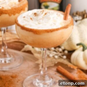 Pumpkin Pie Martini in a glass on a table decorated for a holiday with cinnamon stick on the side of glass