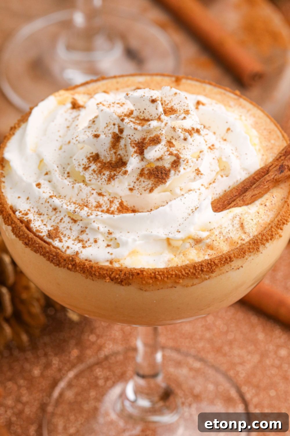close up of a pumpkin martini in glass with whipped cream on top