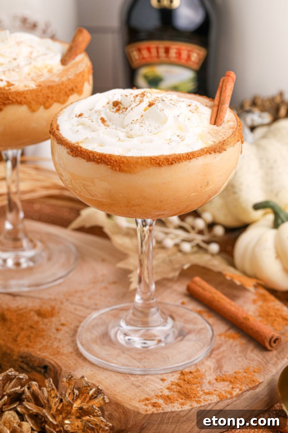 Pumpkin Pie Martinis on table with bottles of alcohol in the background 