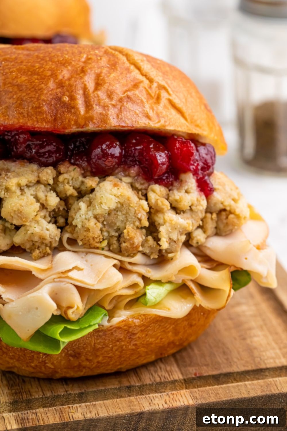 side view of Leftover Turkey Sandwich sitting on a wooden cutting board on table 