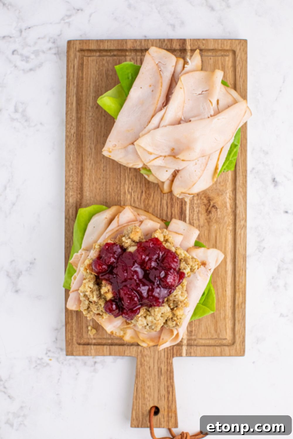 turkey sandwich being assembled with cranberry sauce on top 