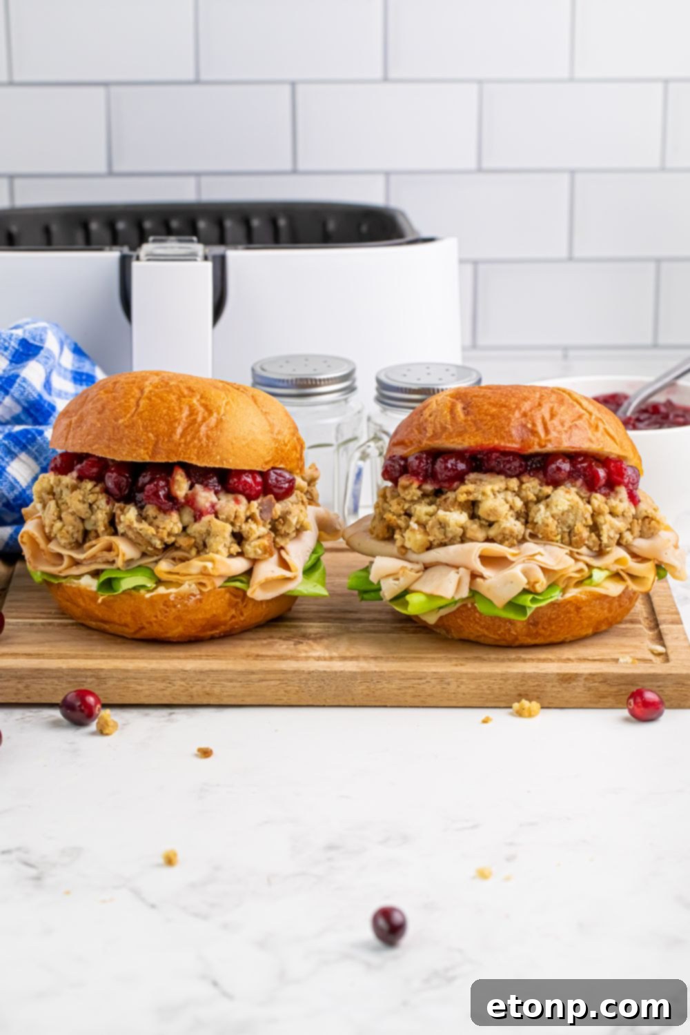 Leftover Turkey Sandwiches sitting on a cutting board on the table with some cranberries on table 