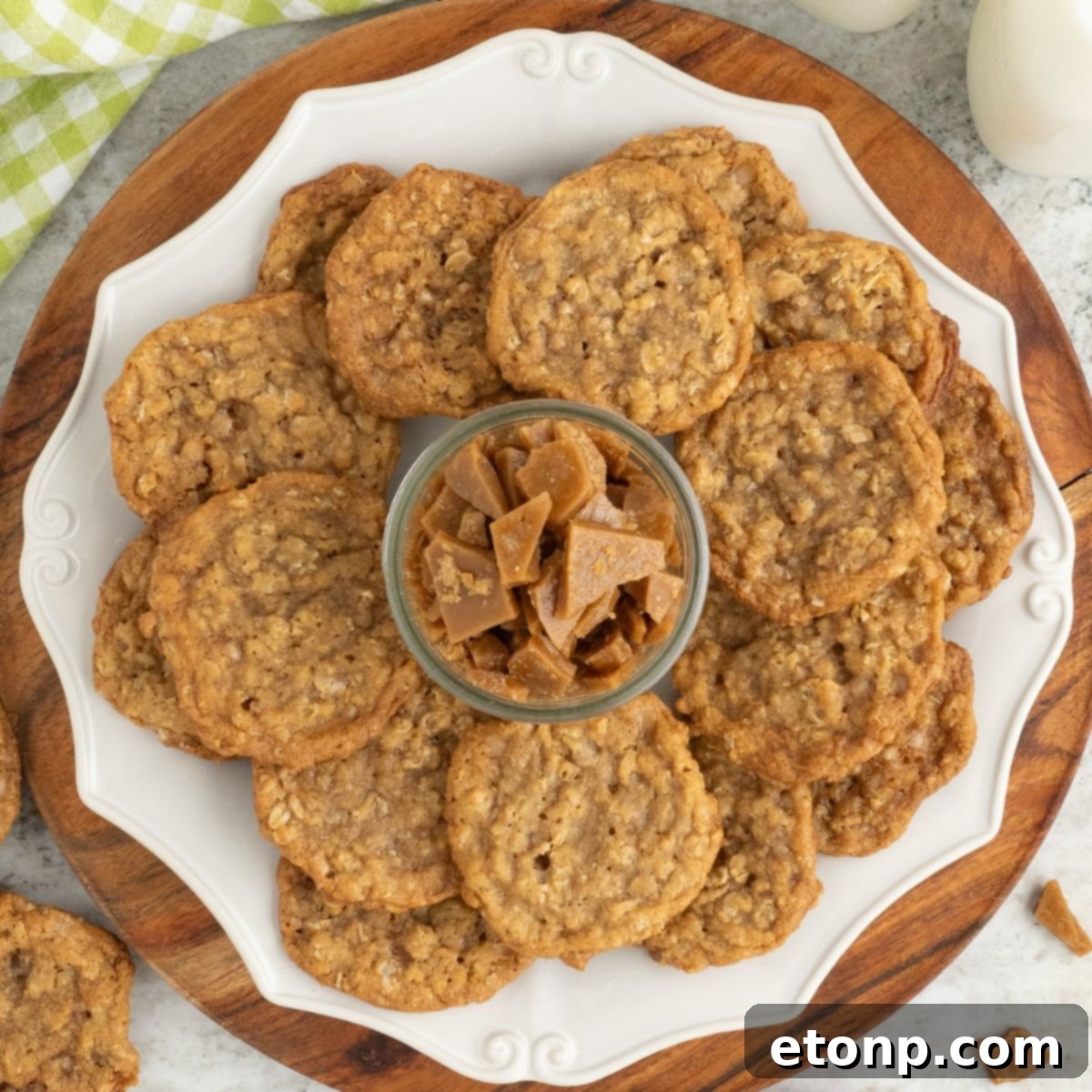 Chewy Toffee Oatmeal Cookies 2 A stack of golden brown Oatmeal Toffee Cookies on a plate, with a small bowl of toffee bits in the center, inviting you to grab one.