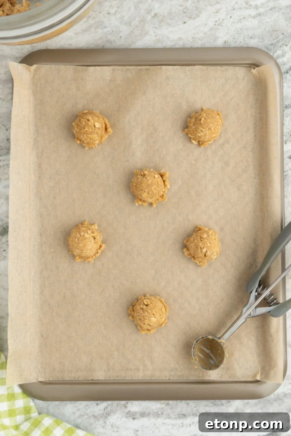 Chewy Toffee Oatmeal Cookies 9 Neatly portioned raw cookie dough balls arranged on a parchment-lined cookie sheet, ready for baking.
