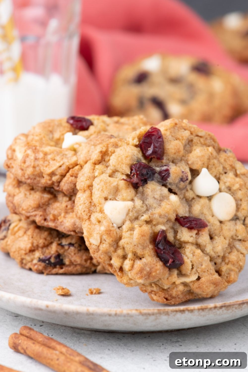 White Chocolate Cranberry Oatmeal Cookies on plate with a cookie tipped on the side 
