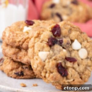 White Chocolate Cranberry Oatmeal Cookies stacked on a plate with one tilted to see cranberries and white chocolate chips on it