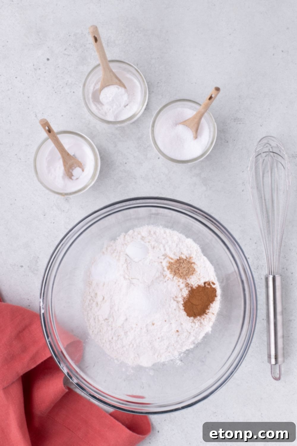 dry ingredients in a large bowl sitting on table with whisk to the side 