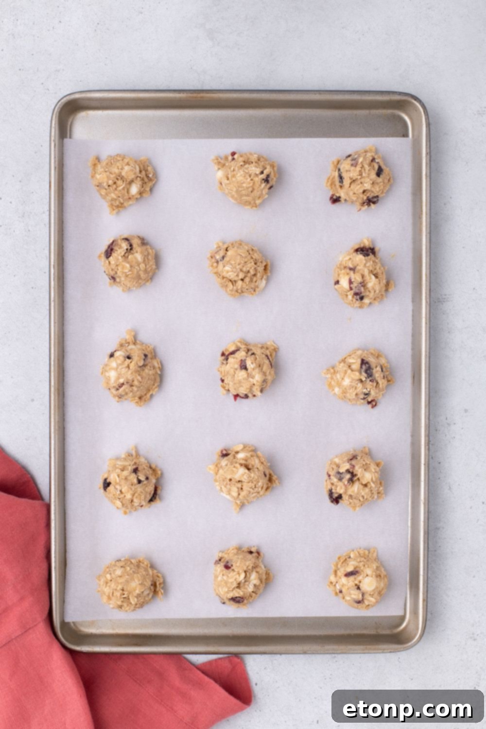 raw White Chocolate Cranberry Oatmeal Cookie dough in balls on a cookie tray on table 