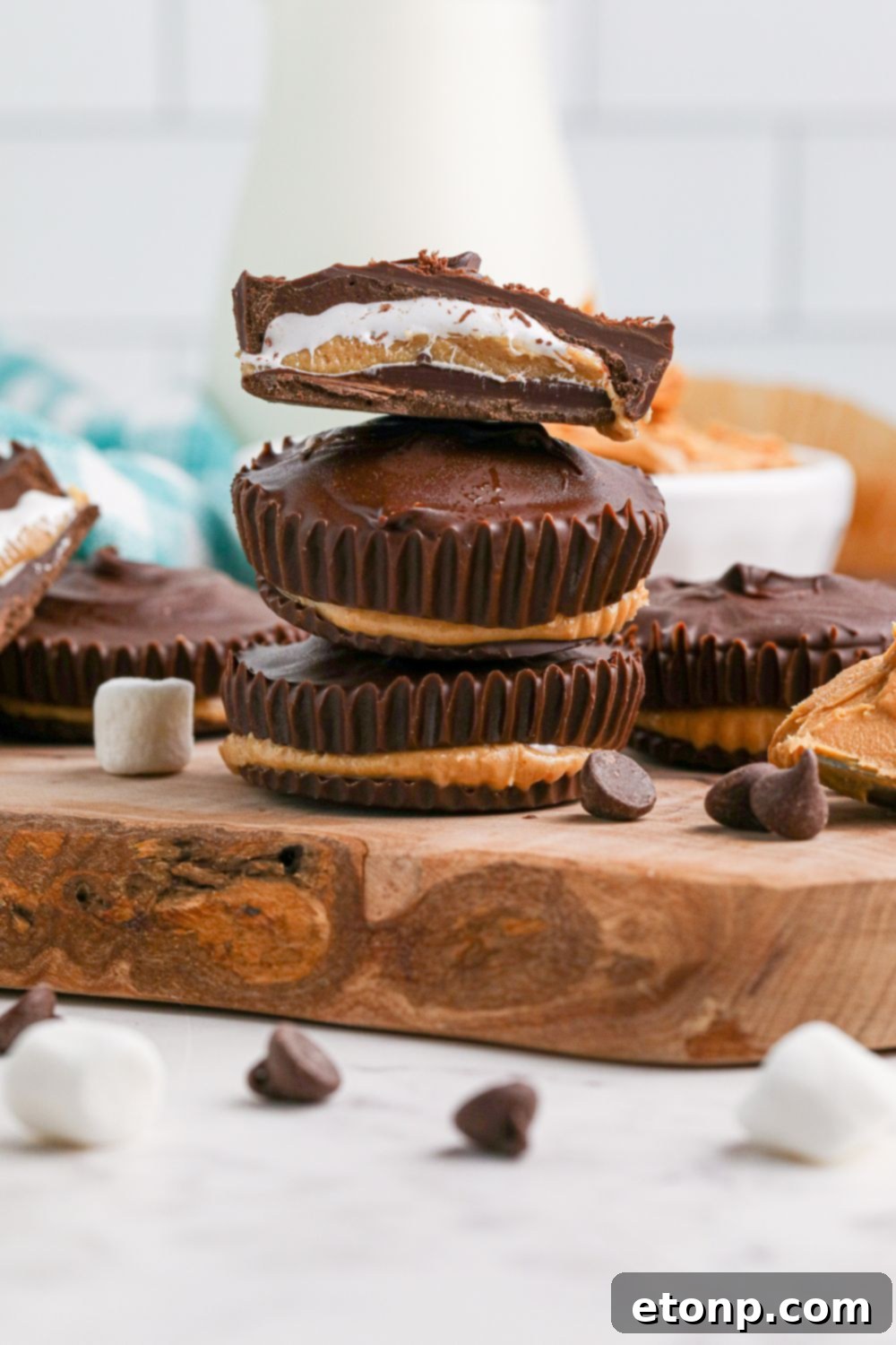 Peanut Butter Marshmallow Cups stacked on wooden tray with one cut in half to see layers 