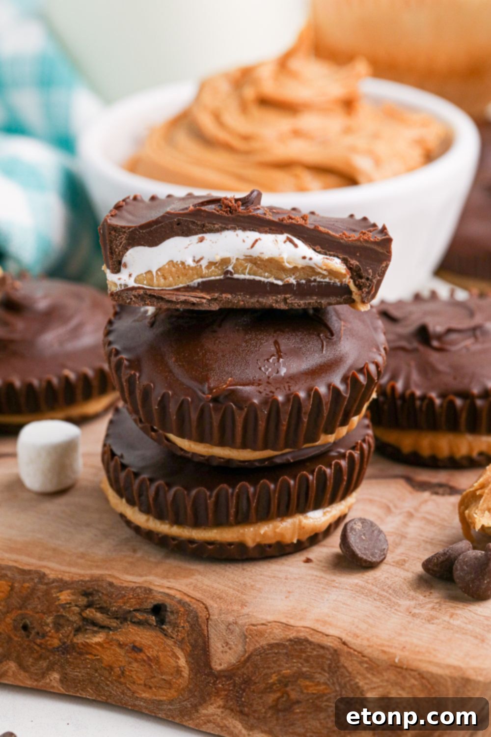stack of Peanut Butter Marshmallow Cups on table with marshmallows and chocolate around it 