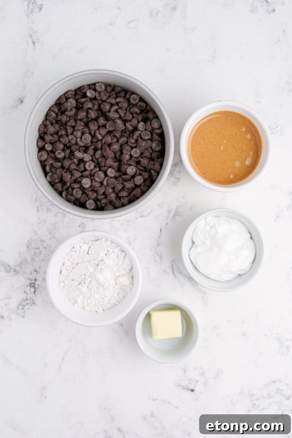 ingredients for Peanut Butter Marshmallow Cups in bowls sitting on marble counter 