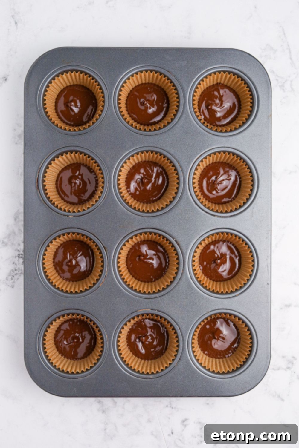 chocolate poured into muffin cup with a liner to make Peanut Butter Marshmallow Cups