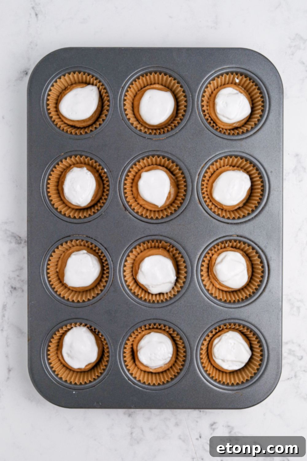 marshmallow cream on top of peanut butter in muffin cups 