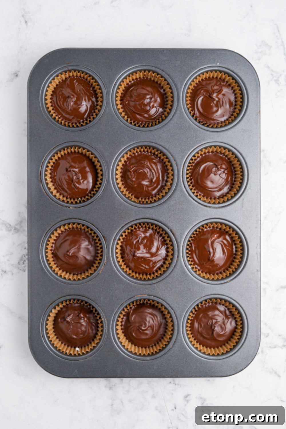 wet chocolate in muffin tin for making Peanut Butter Marshmallow Cups