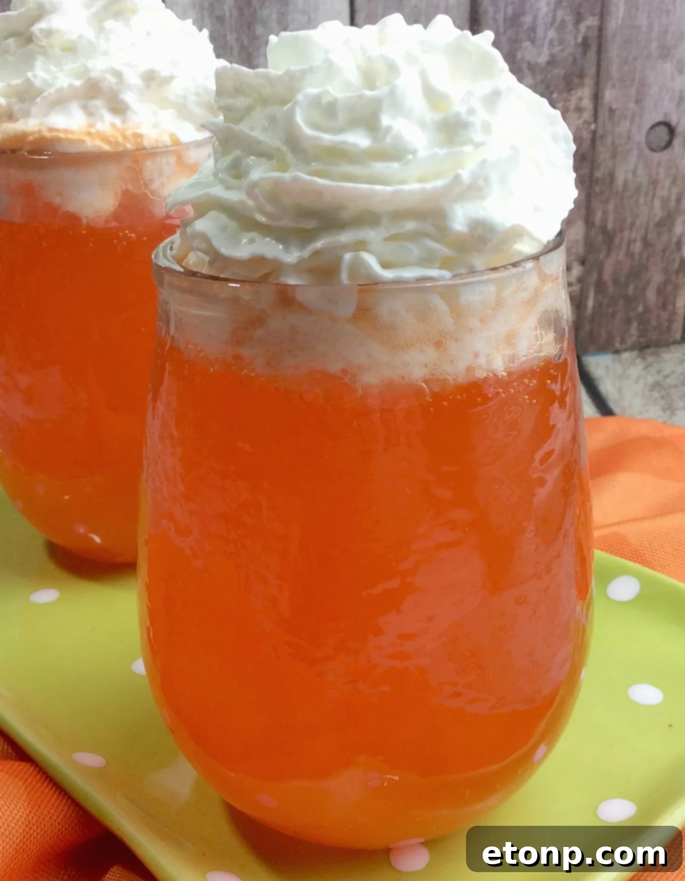 A close-up shot of the finished Orange Creamsicle Cocktail, highlighting the frothy whipped cream topping and a hint of orange.