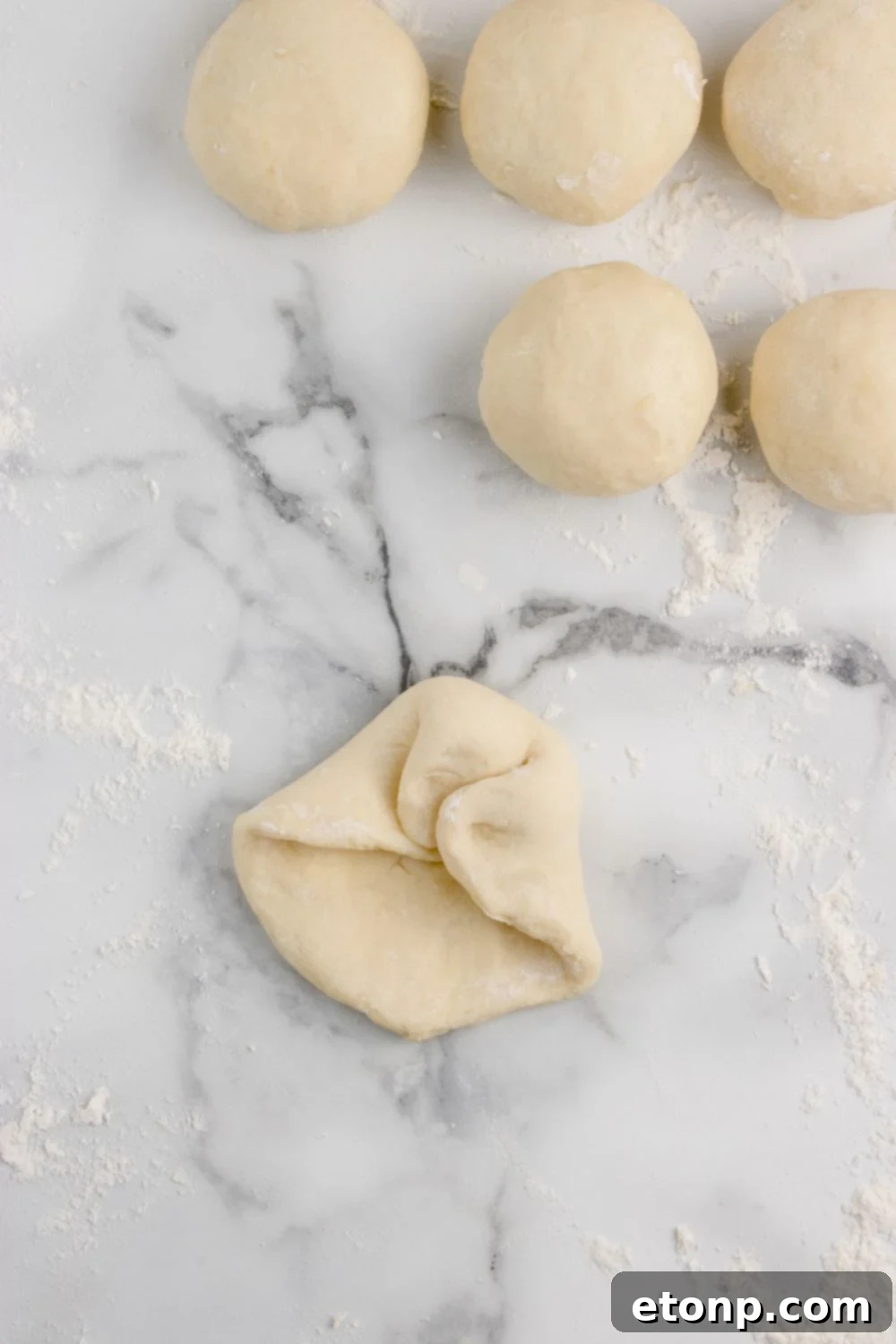 folding up bread dough in balls for making Hawaiian rolls