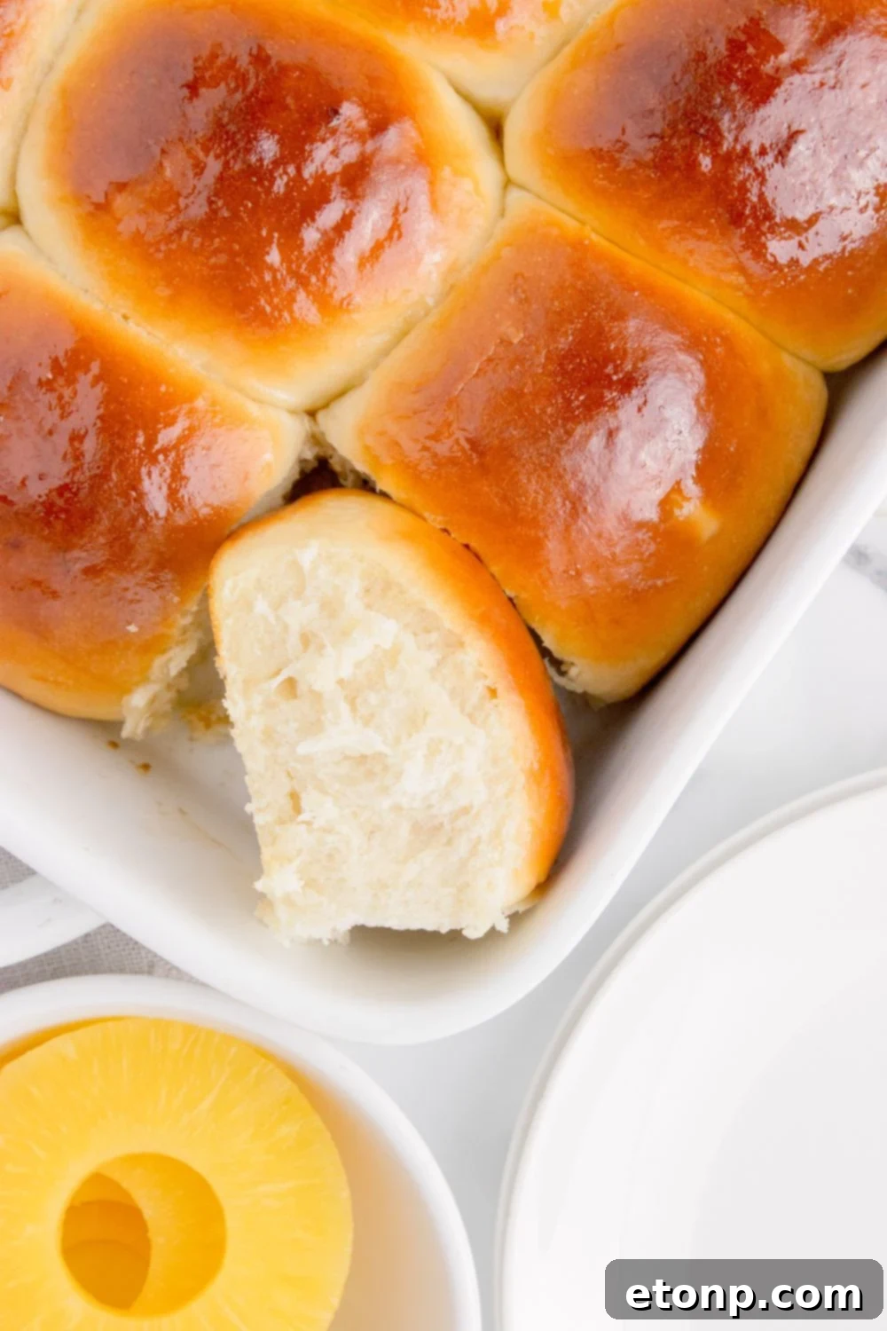 Hawaiian Dinner Rolls in a pan with one tilted on the side to show fluffy texture 