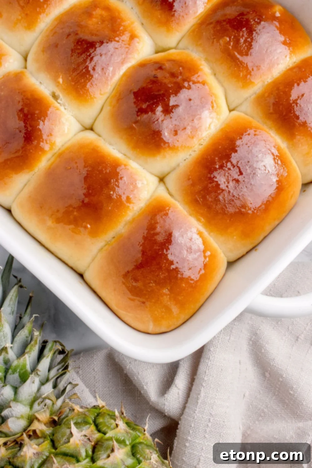 sweet hawaiian rolls in a pan on table with a pineapple on side of table