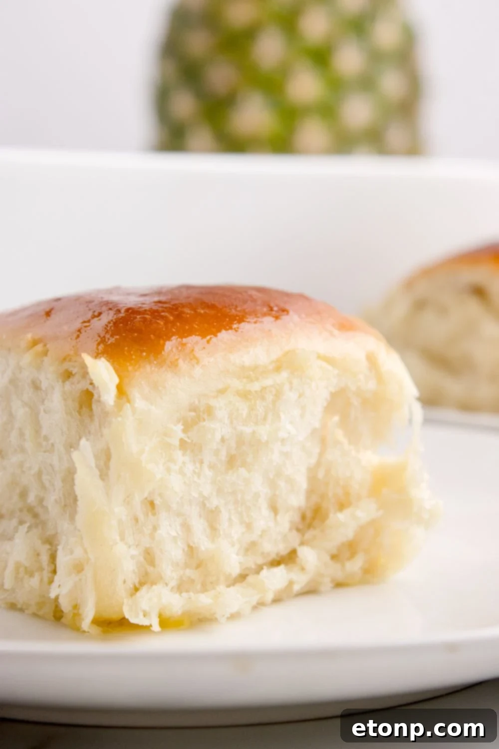 fluffy Hawaiian roll sitting on table with a pineapple sitting in the background