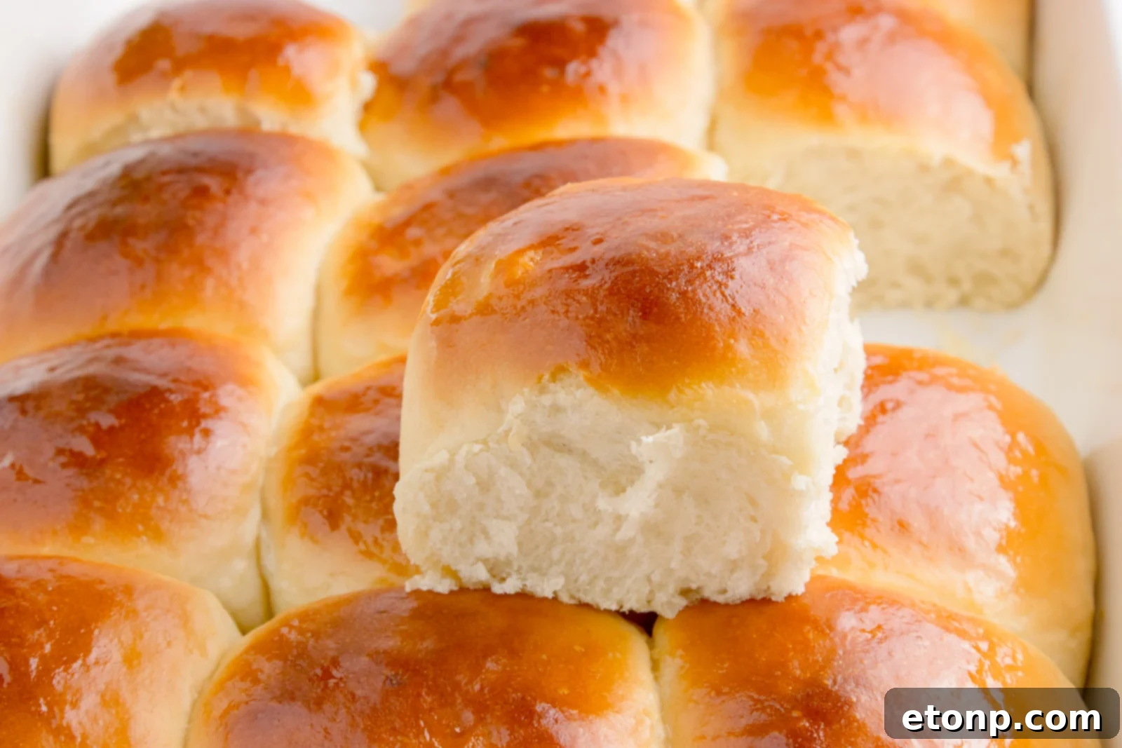 Hawaiian dinner rolls in a baking dish with one removed sitting on top