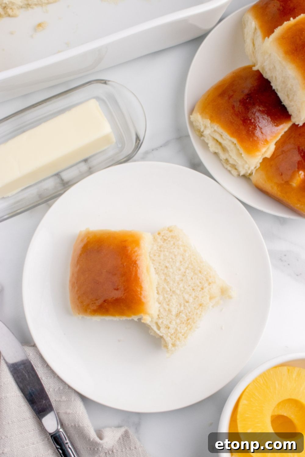 plate of dinner rolls on table, and a slice of bread on plate with a stick of butter on side