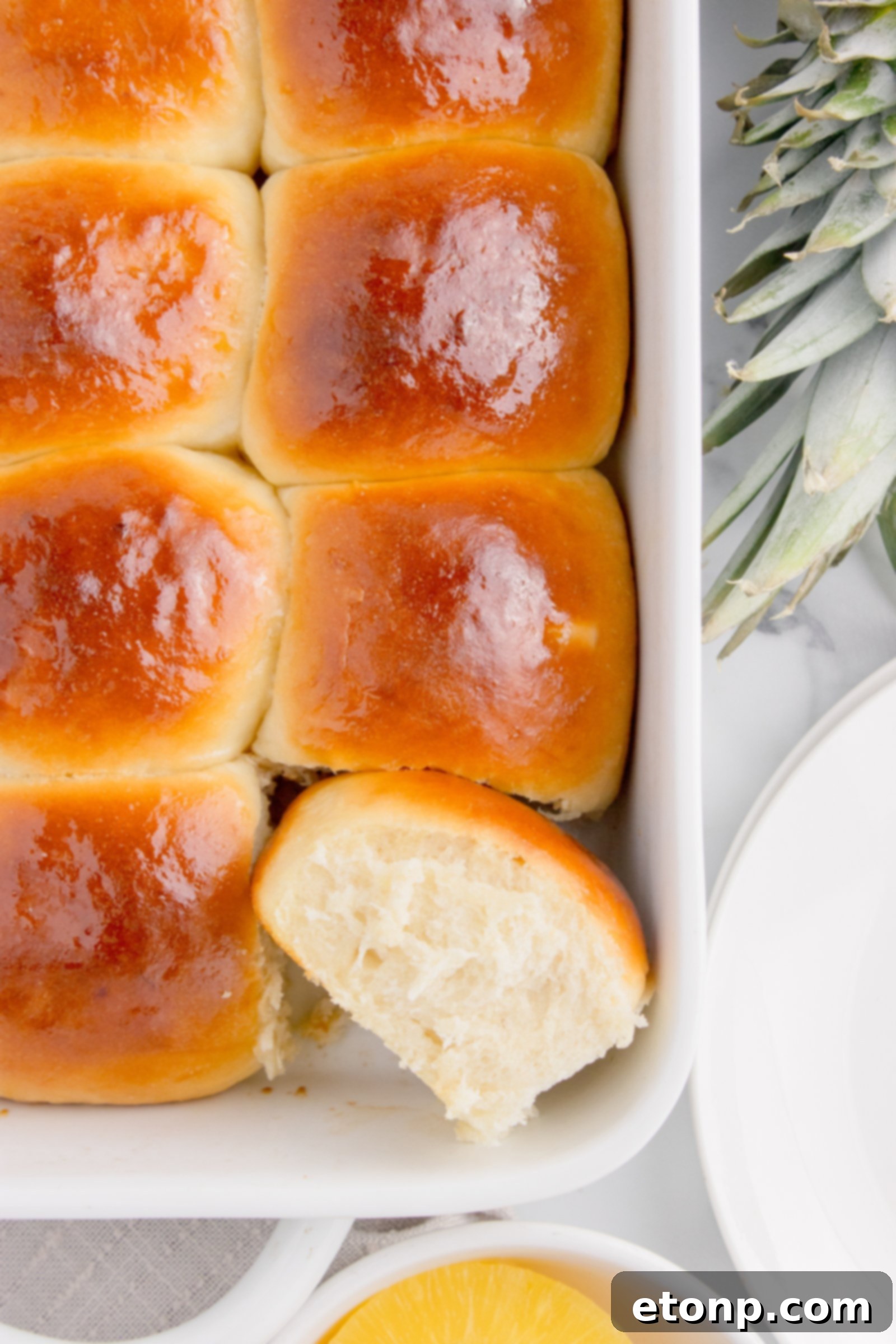 Hawaiian dinner rolls in a baking dish with one on its side showing texture