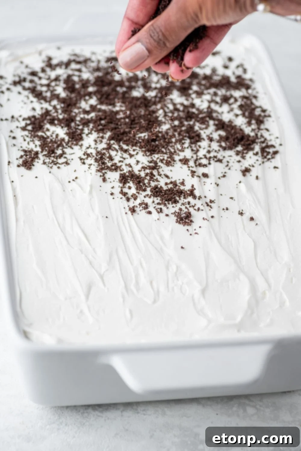 Decadent Chocolate Oreo Dream 11 sprinkling crushed cookies on top of the Chocolate Oreo Lush in pan