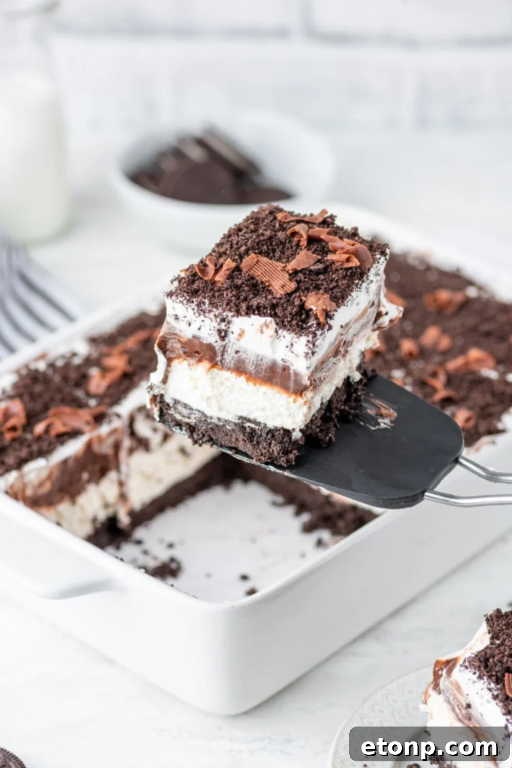 Decadent Chocolate Oreo Dream 15 Chocolate Oreo Lush in a pan with a slice being lifted out of pan with spatula