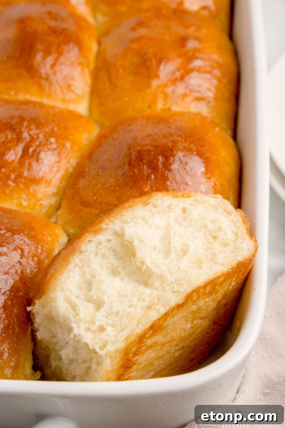 Pull Apart Rolls in a baking dish, with one roll removed and shown open to reveal its fluffy, perfectly baked interior