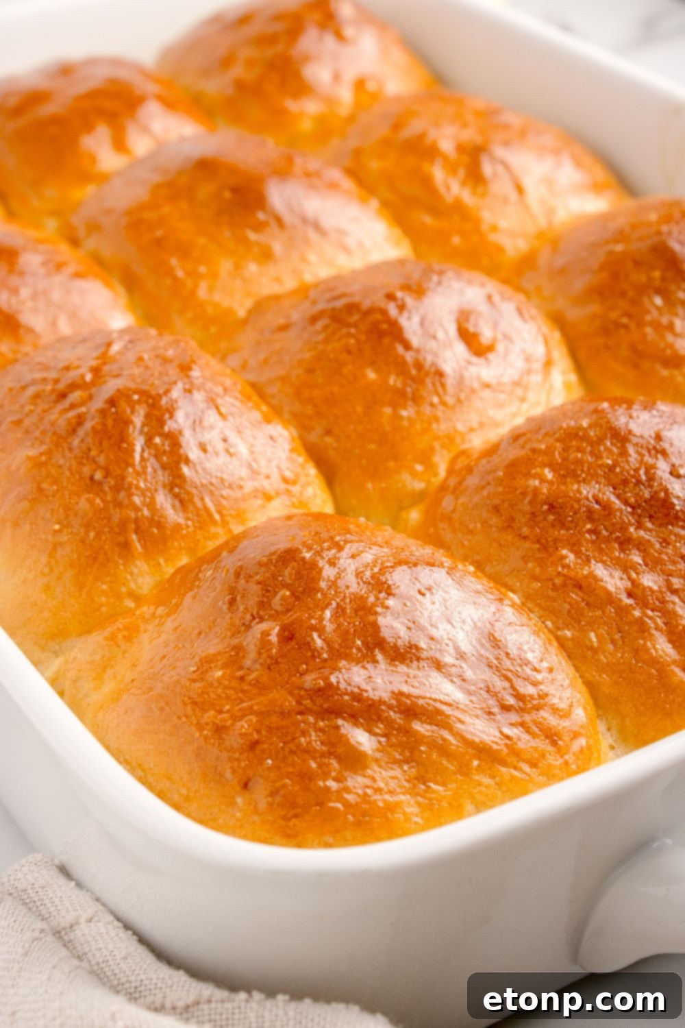 Pull Apart Dinner Rolls in a white casserole pan on a table, highlighting their perfect golden brown tops