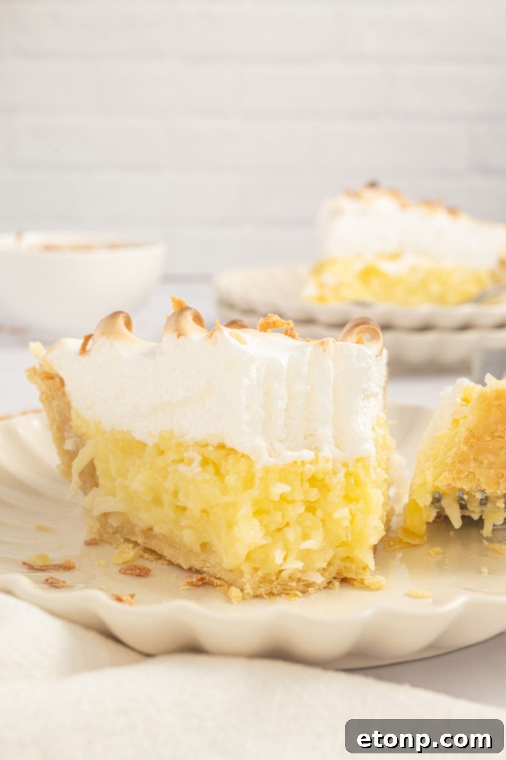 slice of Coconut Meringue Pie on plate with a fork with a bite full on it