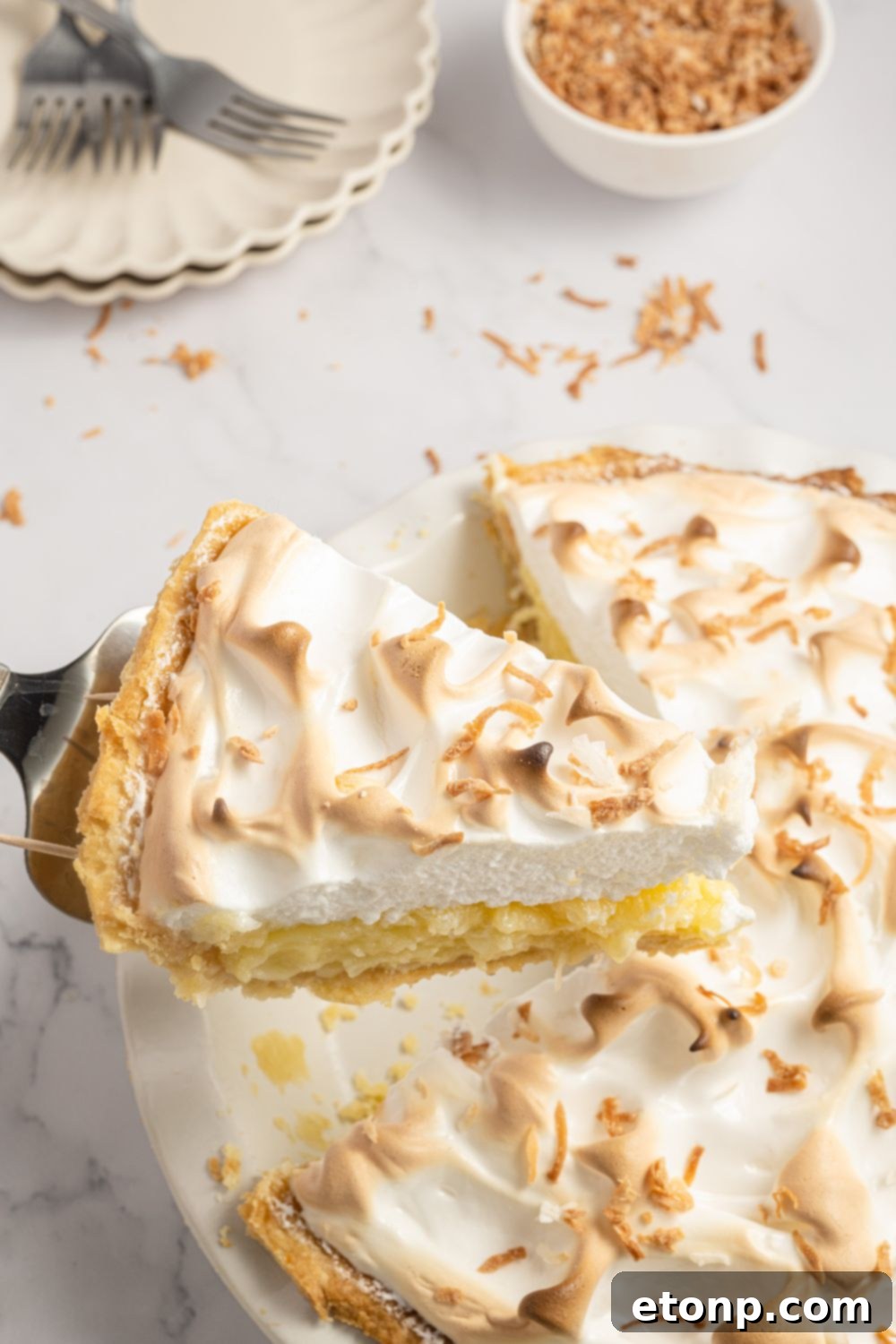 Coconut Meringue Pie on table with one slice being lifted from the pie plate