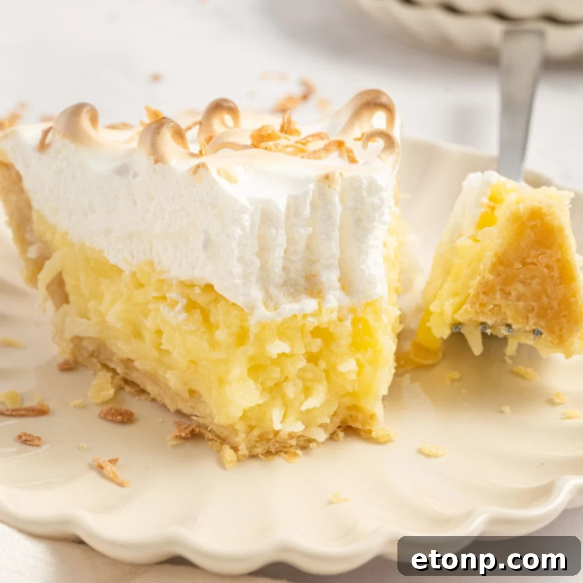 Coconut Meringue Pie on a plate with a fork with a bite on it