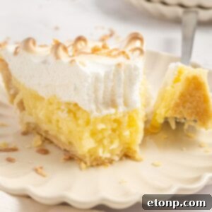 Coconut Meringue Pie on a plate with a fork with a bite on it