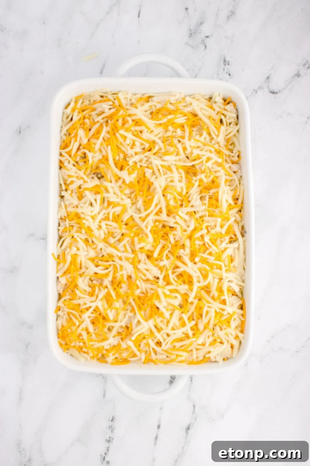 shredded cheese spread out over pan with chicken tetrazzini in pan