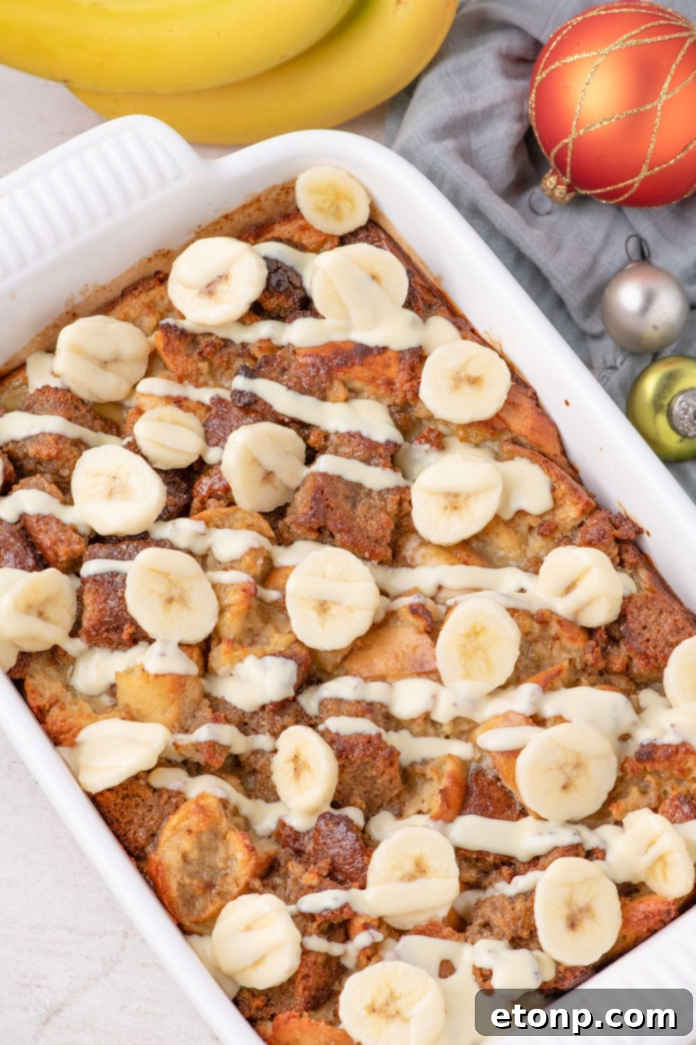 overhead Banana Bread Pudding in dish on table with christmas ornaments around it 