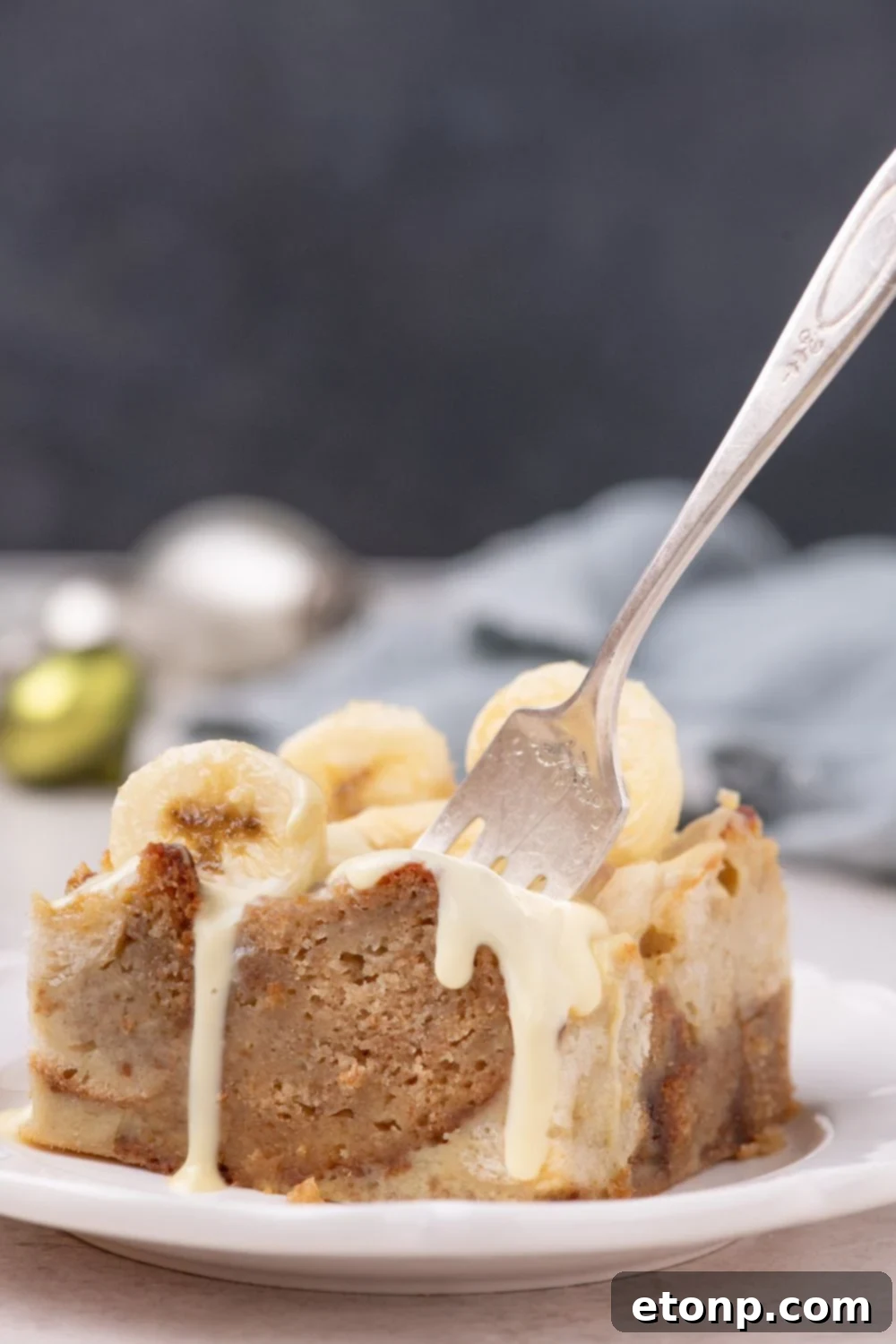 slice of Banana Bread Pudding on plate with a fork poked into it 