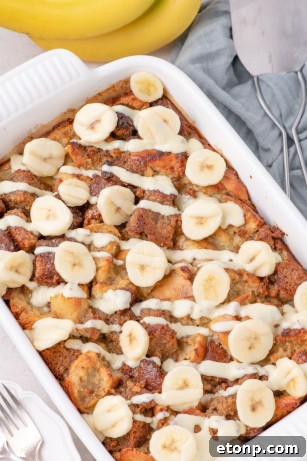 Banana Bread Pudding in a casserole dish topped with sliced bananas 